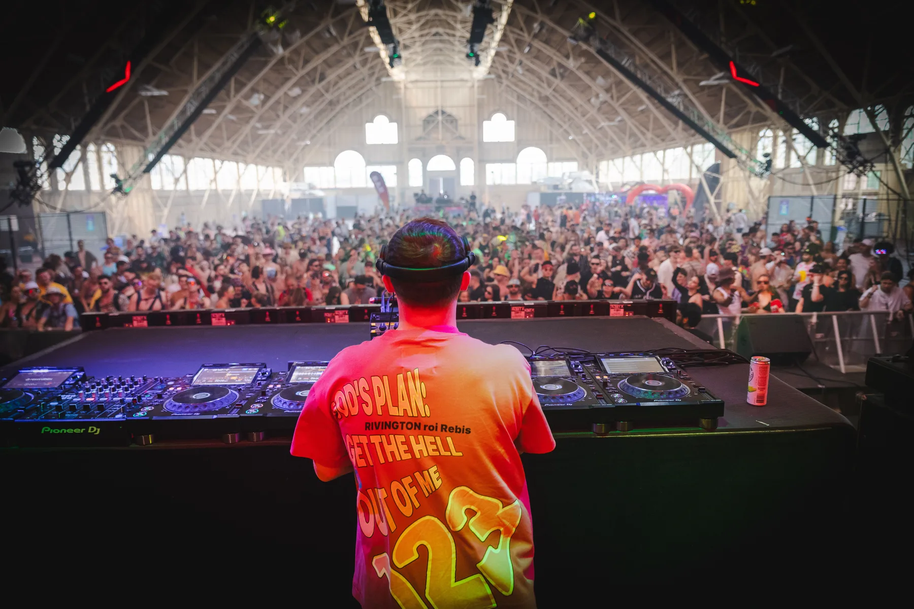 DJ performing for a large crowd inside a packed event venue.